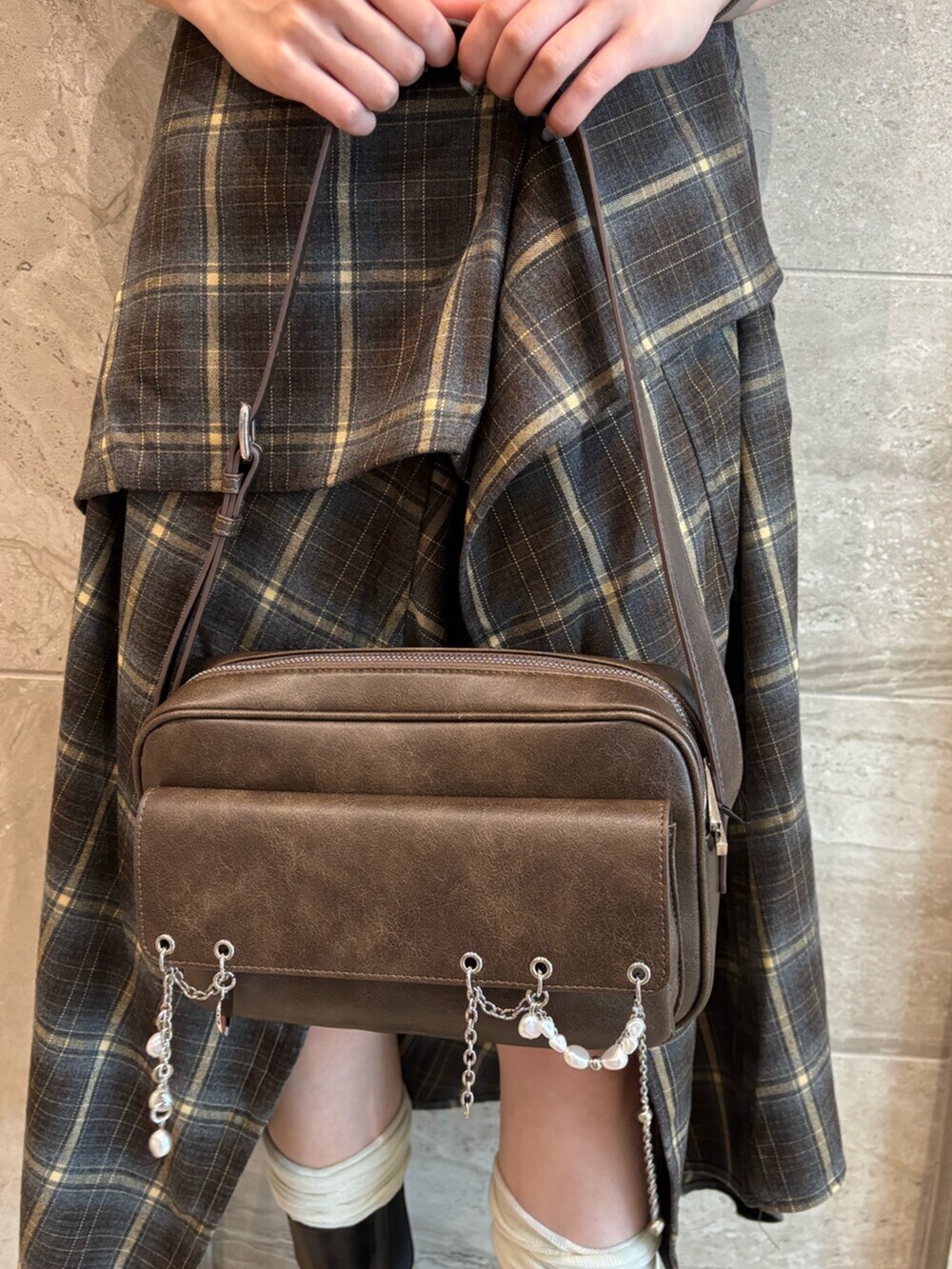 ブラウン系のハンドバッグ、グリーン系のワンピース、ブラック系のブーツを着用したレディースの夏コーディネートの7枚目の写真