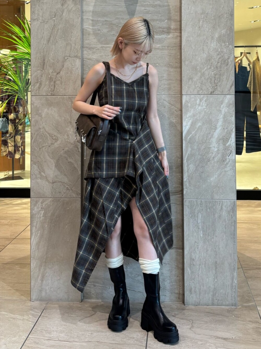 ブラウン系のハンドバッグ、グリーン系のワンピース、ブラック系のブーツを着用したレディースの夏コーディネートの2枚目の写真