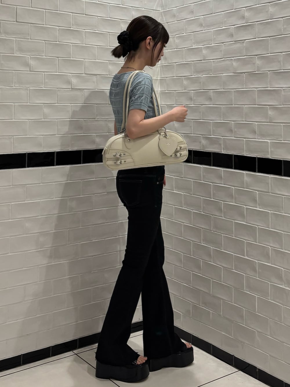 ブルー系のニット/セーター、ブラック系のデニムパンツ、ホワイト系のハンドバッグを着用したレディースの春コーディネートの2枚目の写真