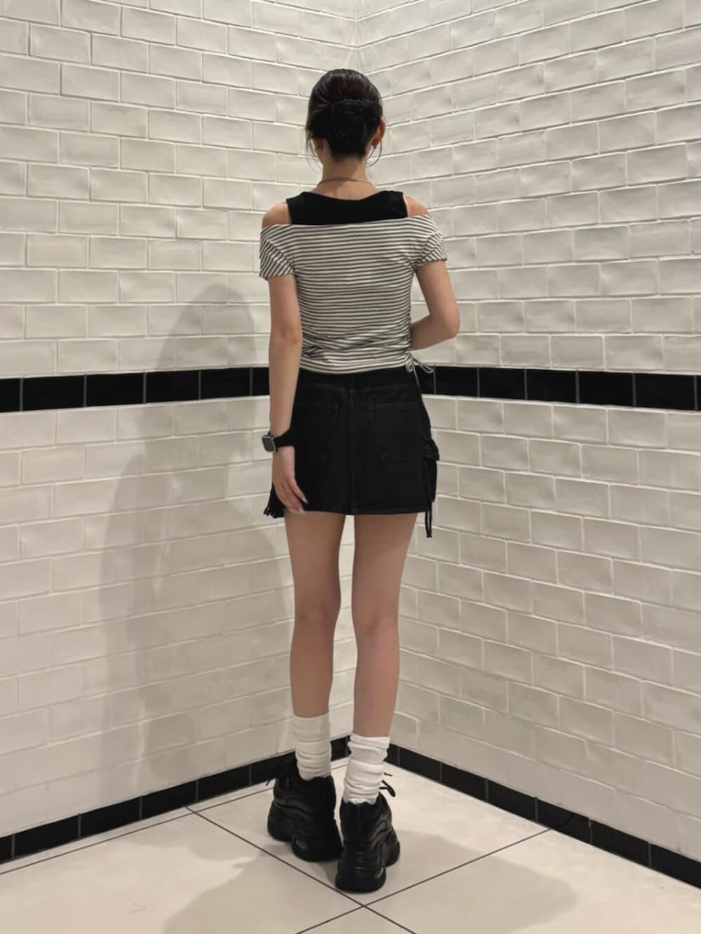 ブラック系のスニーカー、ブラック系のスカート、ホワイト系のTシャツ/カットソーを着用したレディースの夏コーディネートの3枚目の写真