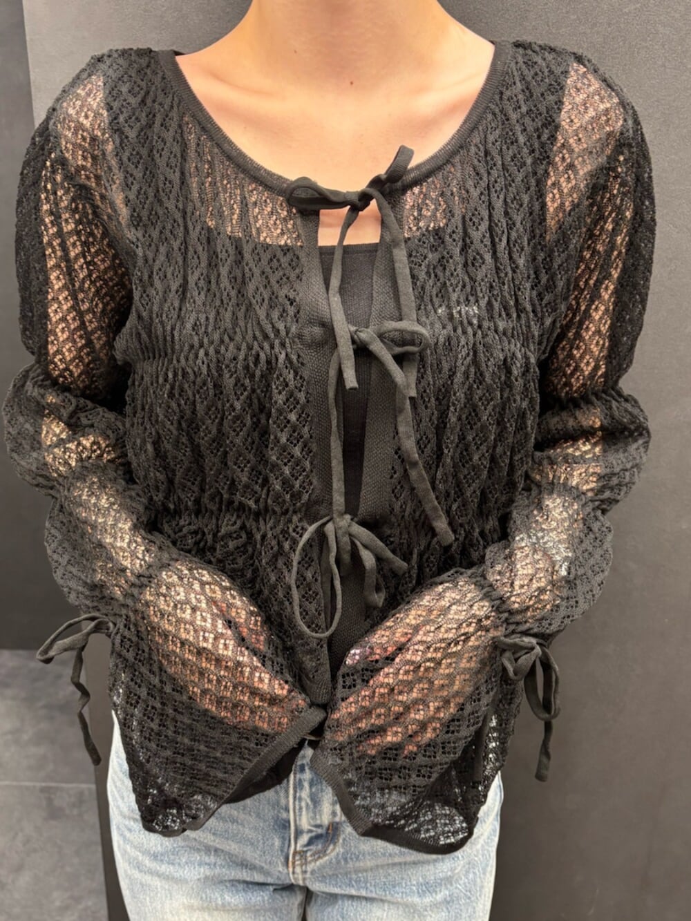 ブラック系のスニーカー、ブルー系のデニムパンツ、ブラック系のニット/セーターを着用したレディースの春コーディネートの4枚目の写真