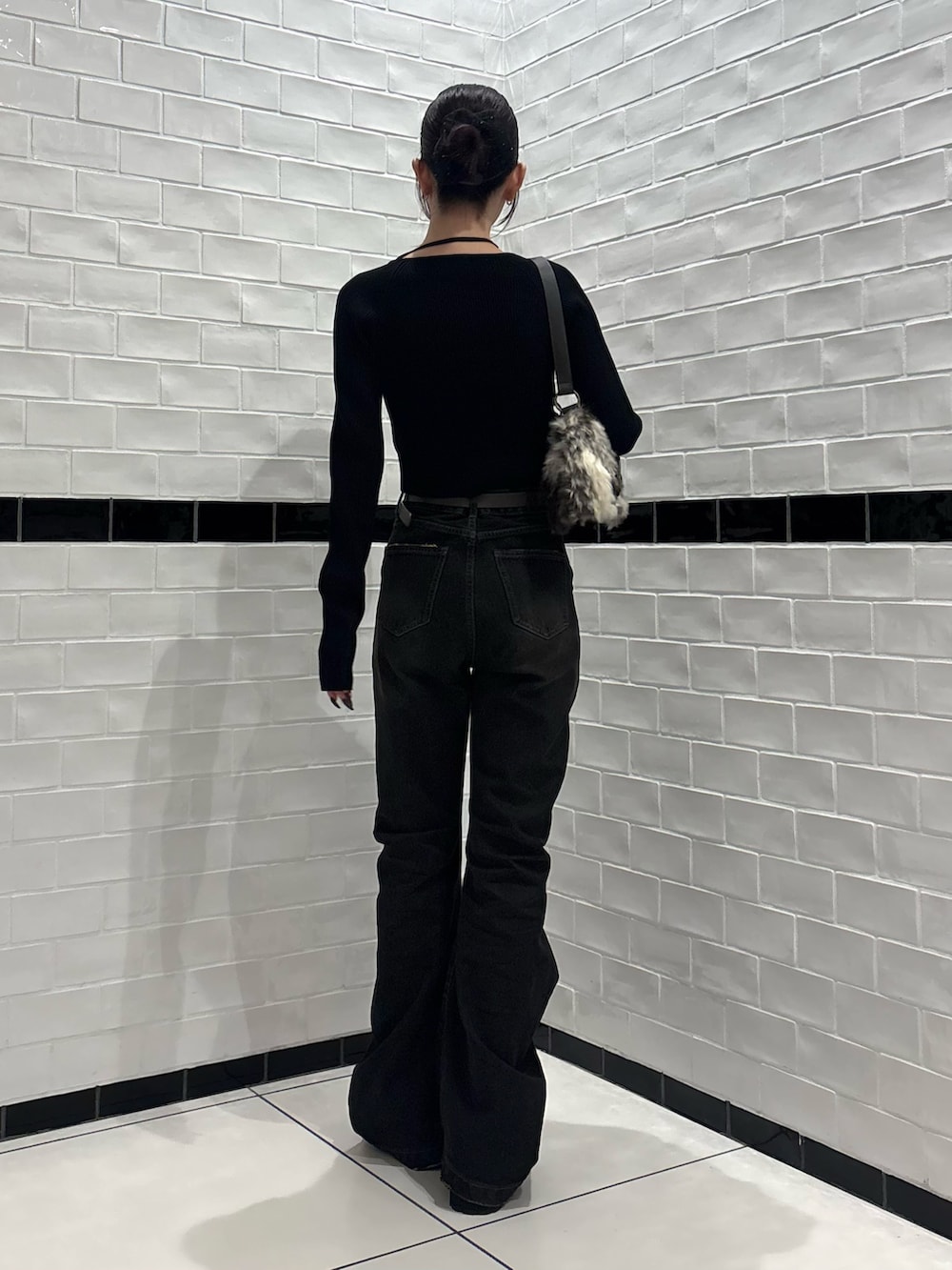 ブラック系のニット/セーター、ブラック系のデニムパンツ、ブラウン系のショルダーバッグを着用したレディースの秋コーディネートの3枚目の写真