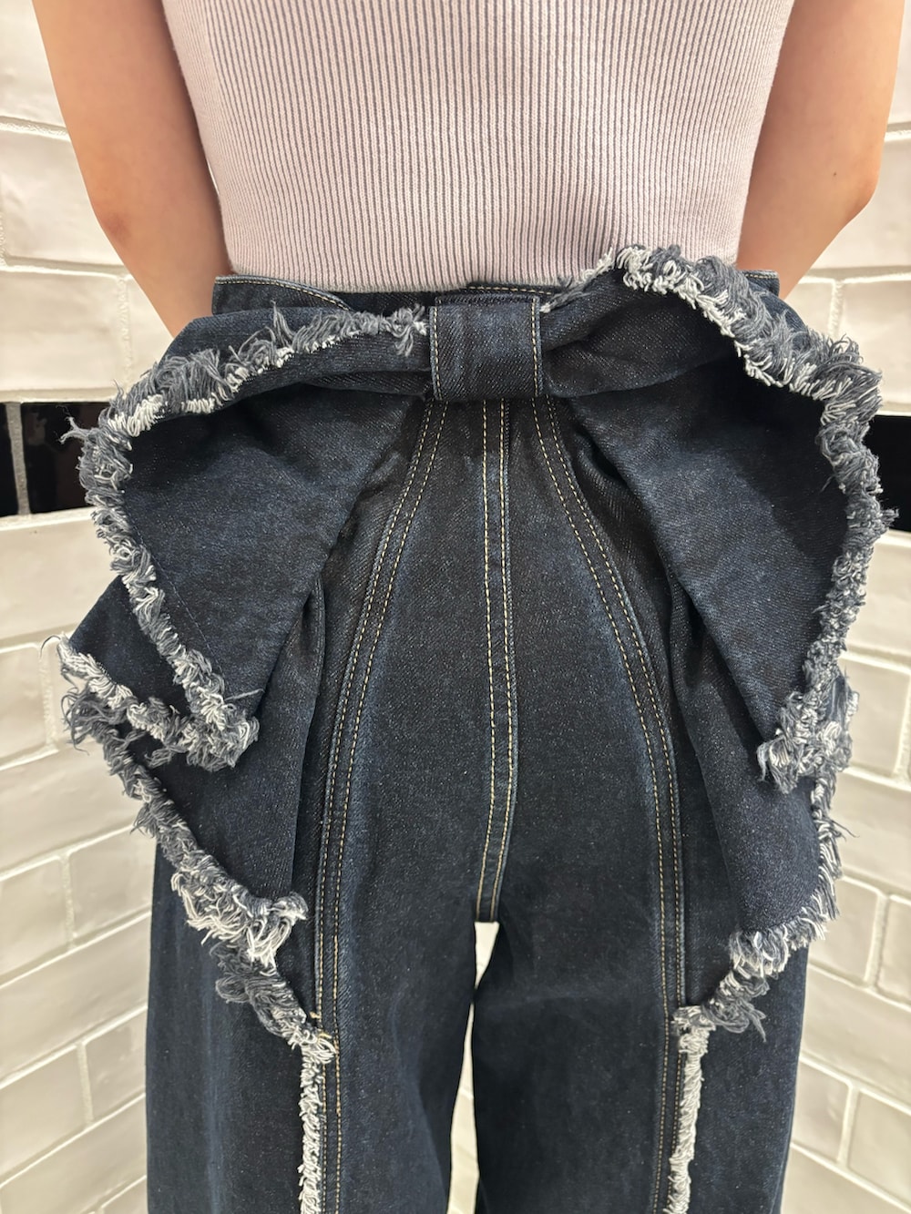 ピンク系のニット/セーター、ブルー系のデニムパンツ、ブラック系のショルダーバッグを着用したレディースの夏コーディネートの7枚目の写真