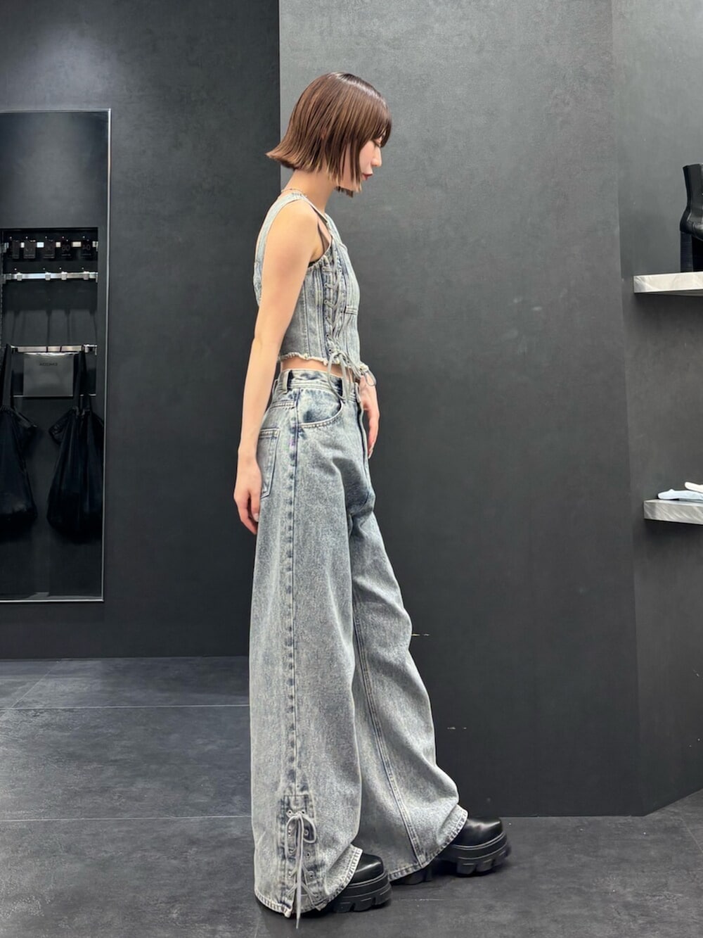 ブラック系のブーツ、ブルー系のタンクトップ、ブルー系のデニムパンツを着用したレディースの春コーディネートの2枚目の写真