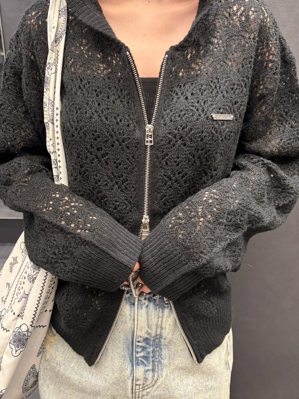 ブラック系のパーカー、ブルー系のデニムパンツ、ブラック系のスニーカーを着用したレディースの春コーディネートの4枚目の写真