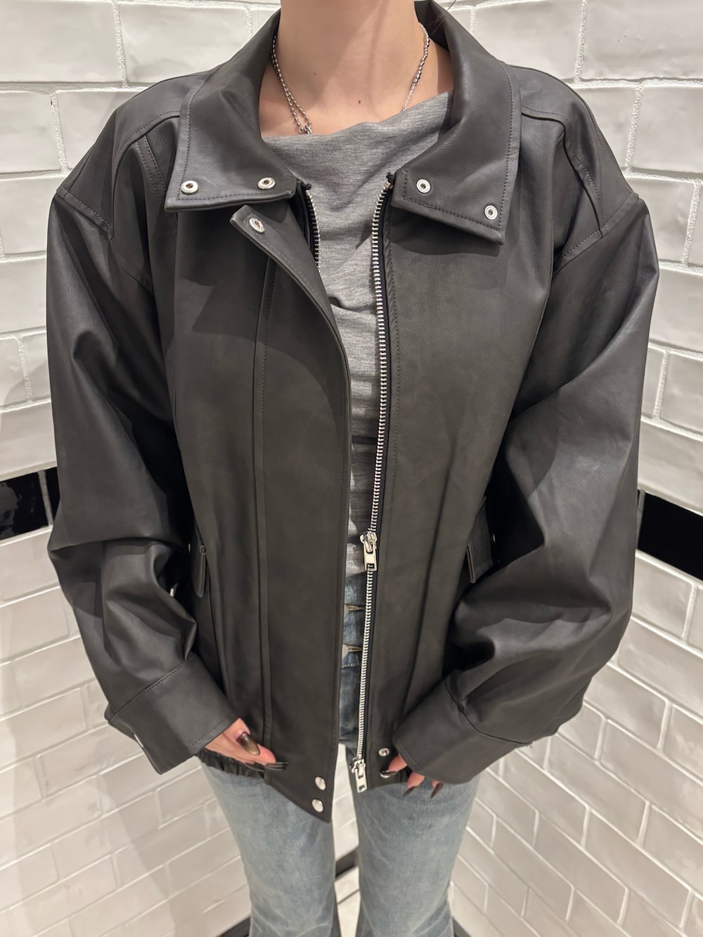 ブラック系のブルゾン、ブルー系のデニムパンツ、ブラック系のブーツを着用したレディースの秋コーディネートの4枚目の写真