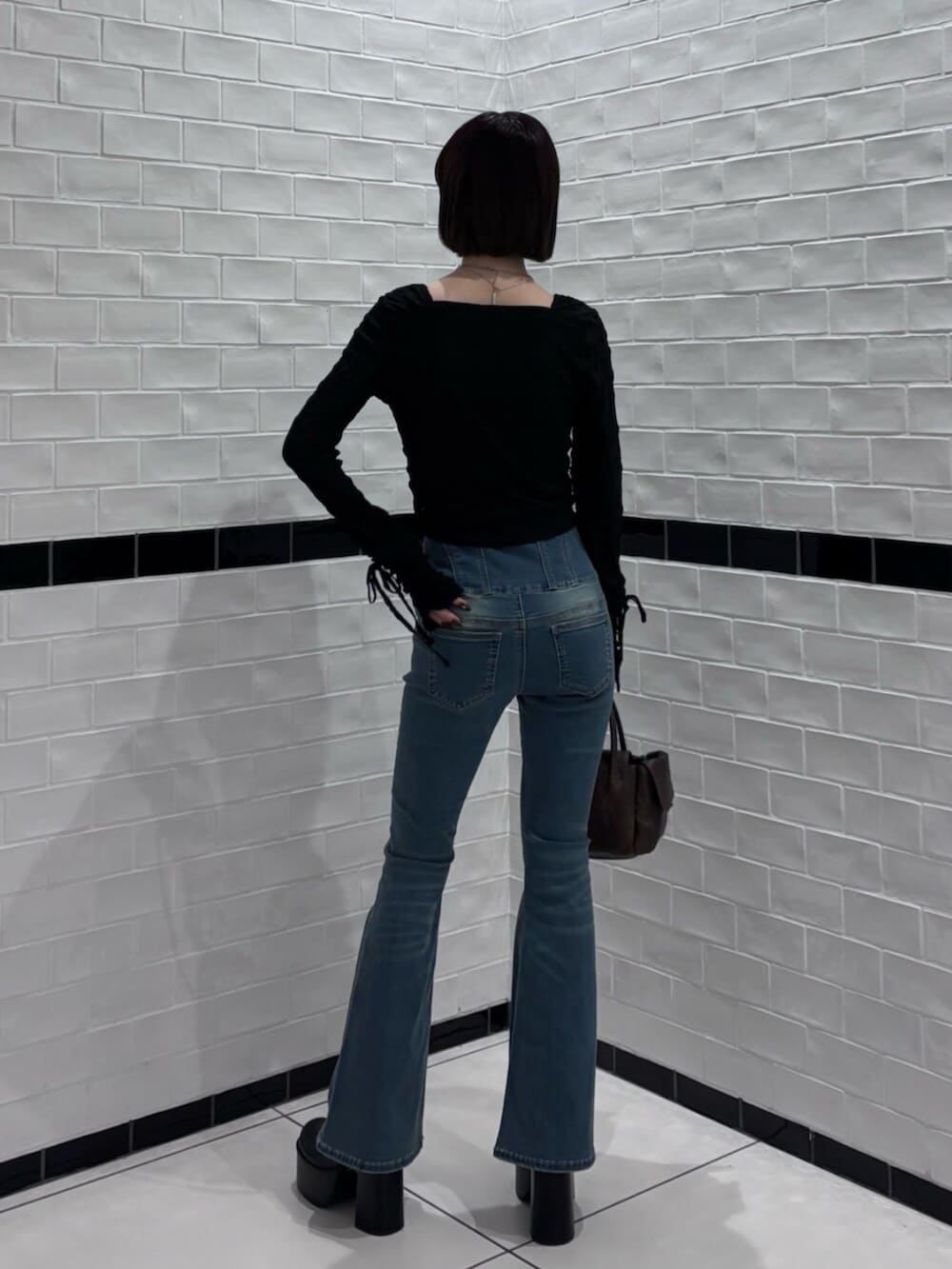 ブラック系のブーツ、ブラウン系のハンドバッグ、ブラック系のTシャツ/カットソーを着用したレディースの冬コーディネートの3枚目の写真