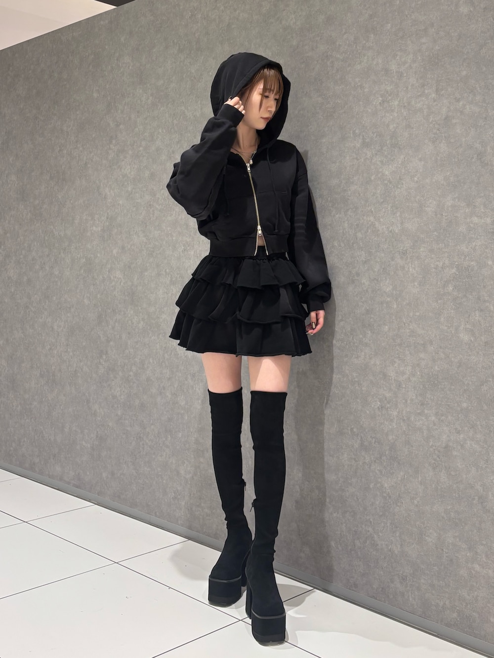 ブラック系のパーカー、ブラック系のスカート、ブラック系のブーツを着用したレディースの秋コーディネートの2枚目の写真