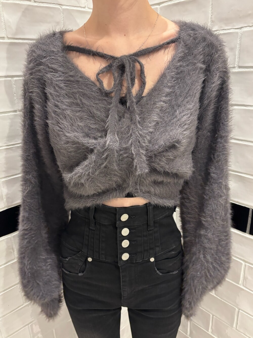 グレー系のニット/セーター、ブラック系のデニムパンツ、ブラック系のブーツを着用したレディースの秋コーディネートの4枚目の写真