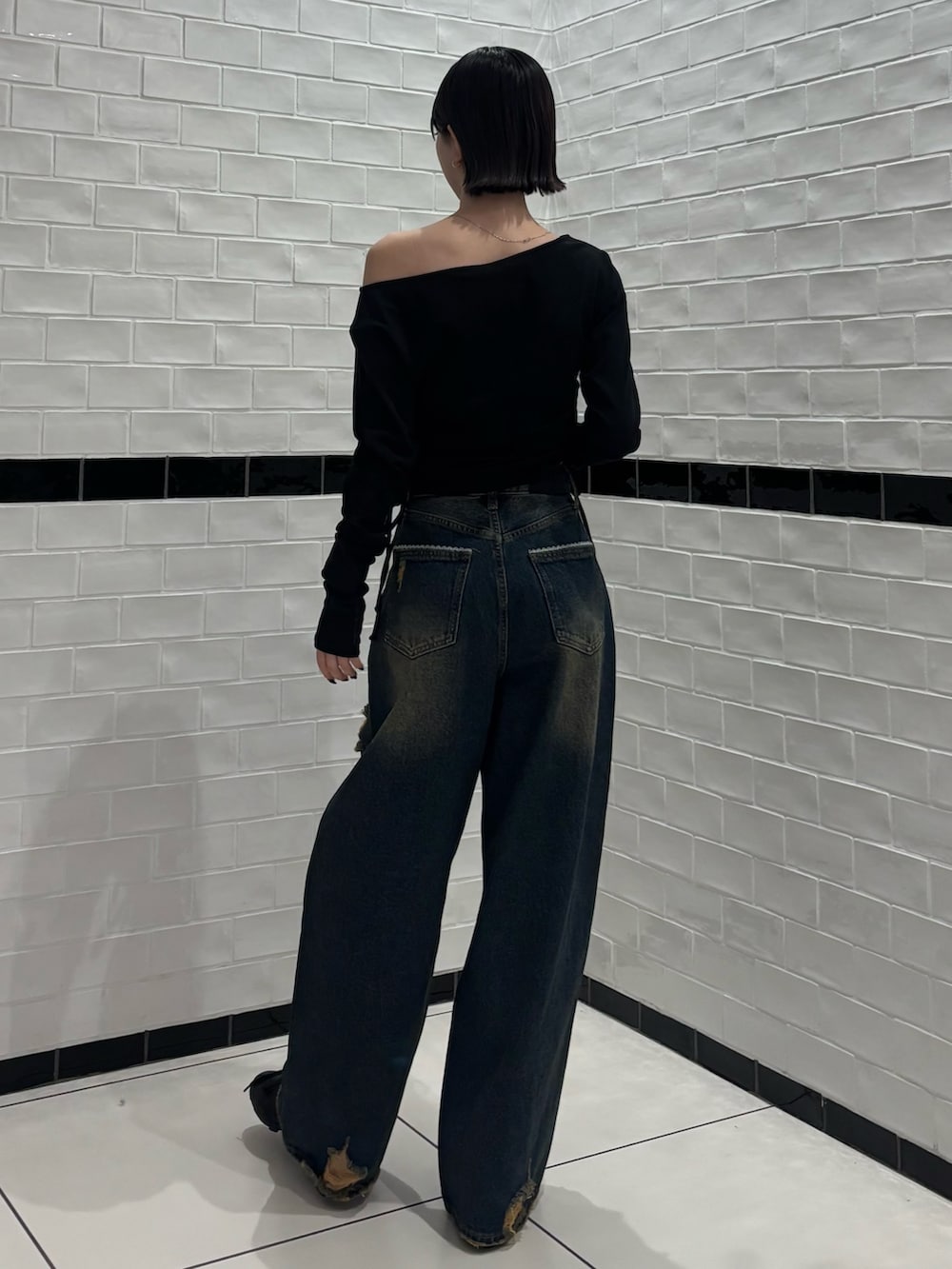 ブラック系のTシャツ/カットソー、ブルー系のデニムパンツ、ブラック系のスニーカーを着用したレディースの春コーディネートの3枚目の写真