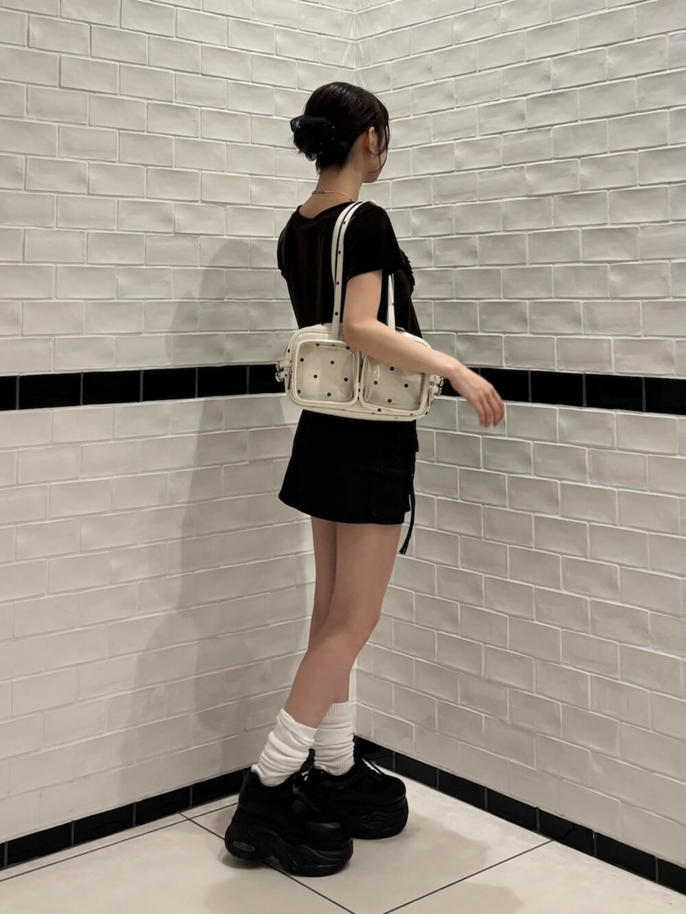 ホワイト系のショルダーバッグ、ブラウン系のTシャツ/カットソー、ブラック系のスニーカーを着用したレディースの夏コーディネートの2枚目の写真