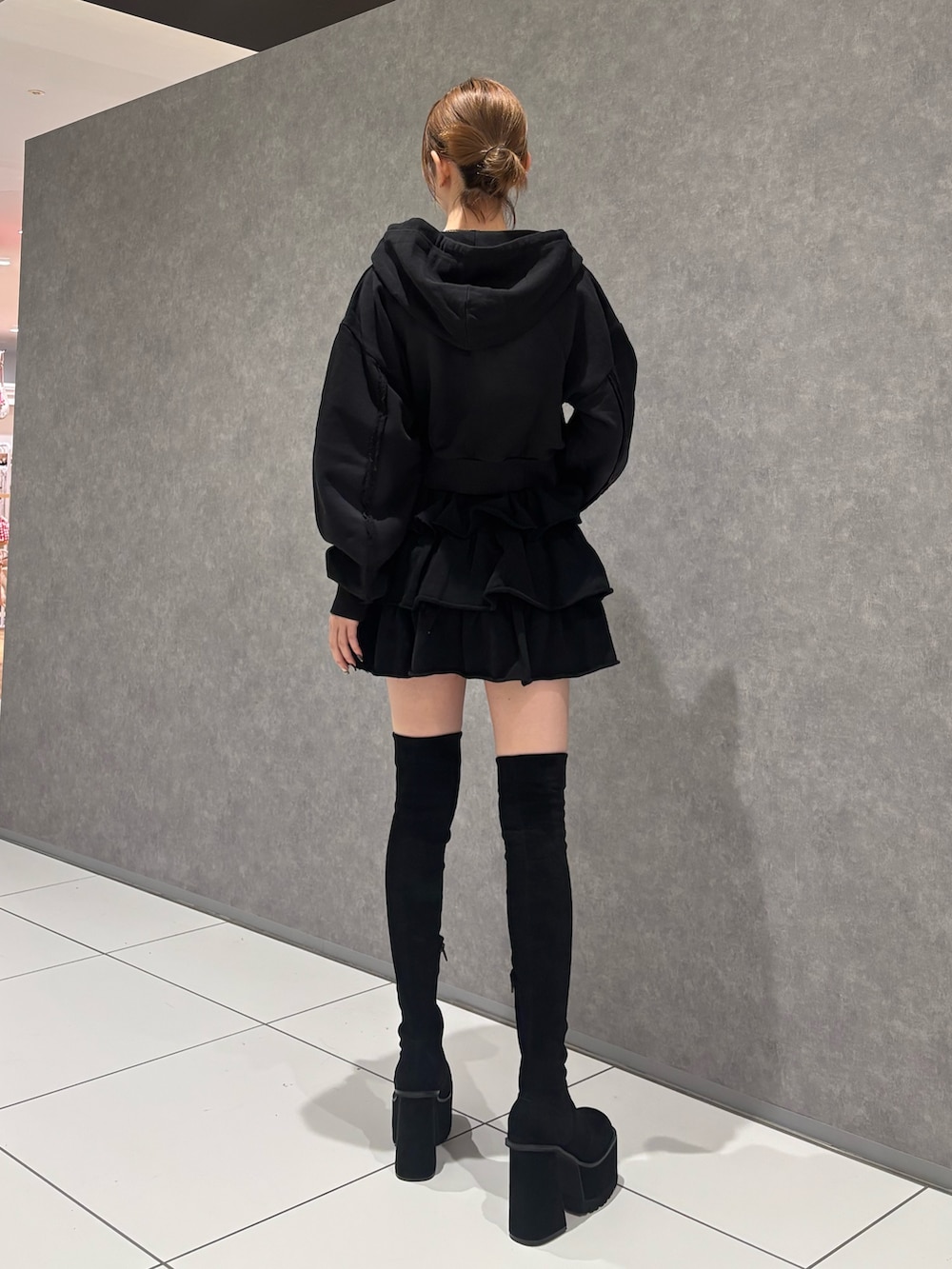 ブラック系のパーカー、ブラック系のスカート、ブラック系のブーツを着用したレディースの秋コーディネートの4枚目の写真