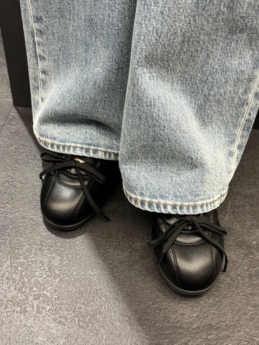 ブラック系のスニーカー、ブルー系のデニムパンツ、ベージュ系のシャツ/ブラウスを着用したレディースの春コーディネートの6枚目の写真