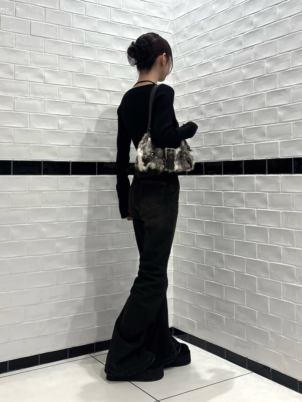 ブラック系のニット/セーター、ブラック系のデニムパンツ、ブラウン系のショルダーバッグを着用したレディースの秋コーディネートの2枚目の写真