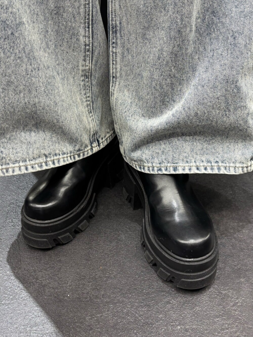 ブラック系のブーツ、ブルー系のタンクトップ、ブルー系のデニムパンツを着用したレディースの春コーディネートの6枚目の写真