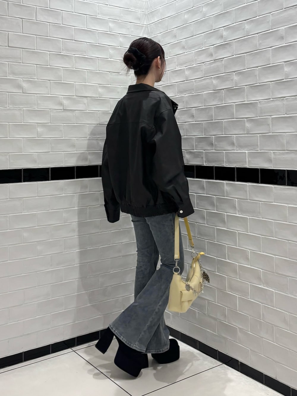 ブラック系のブルゾン、ブルー系のデニムパンツ、ブラック系のブーツを着用したレディースの秋コーディネートの2枚目の写真