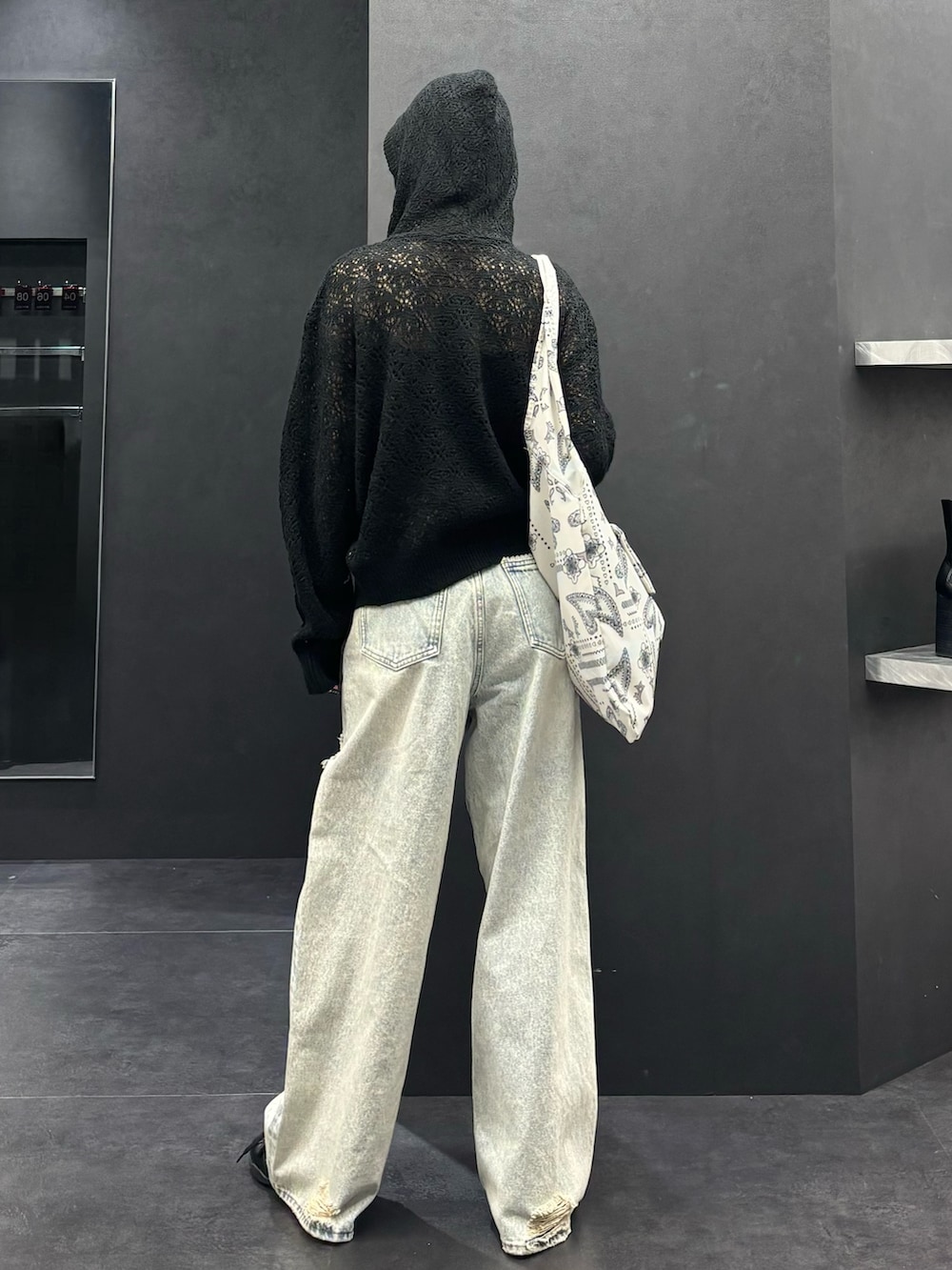 ブラック系のパーカー、ブルー系のデニムパンツ、ブラック系のスニーカーを着用したレディースの春コーディネートの3枚目の写真