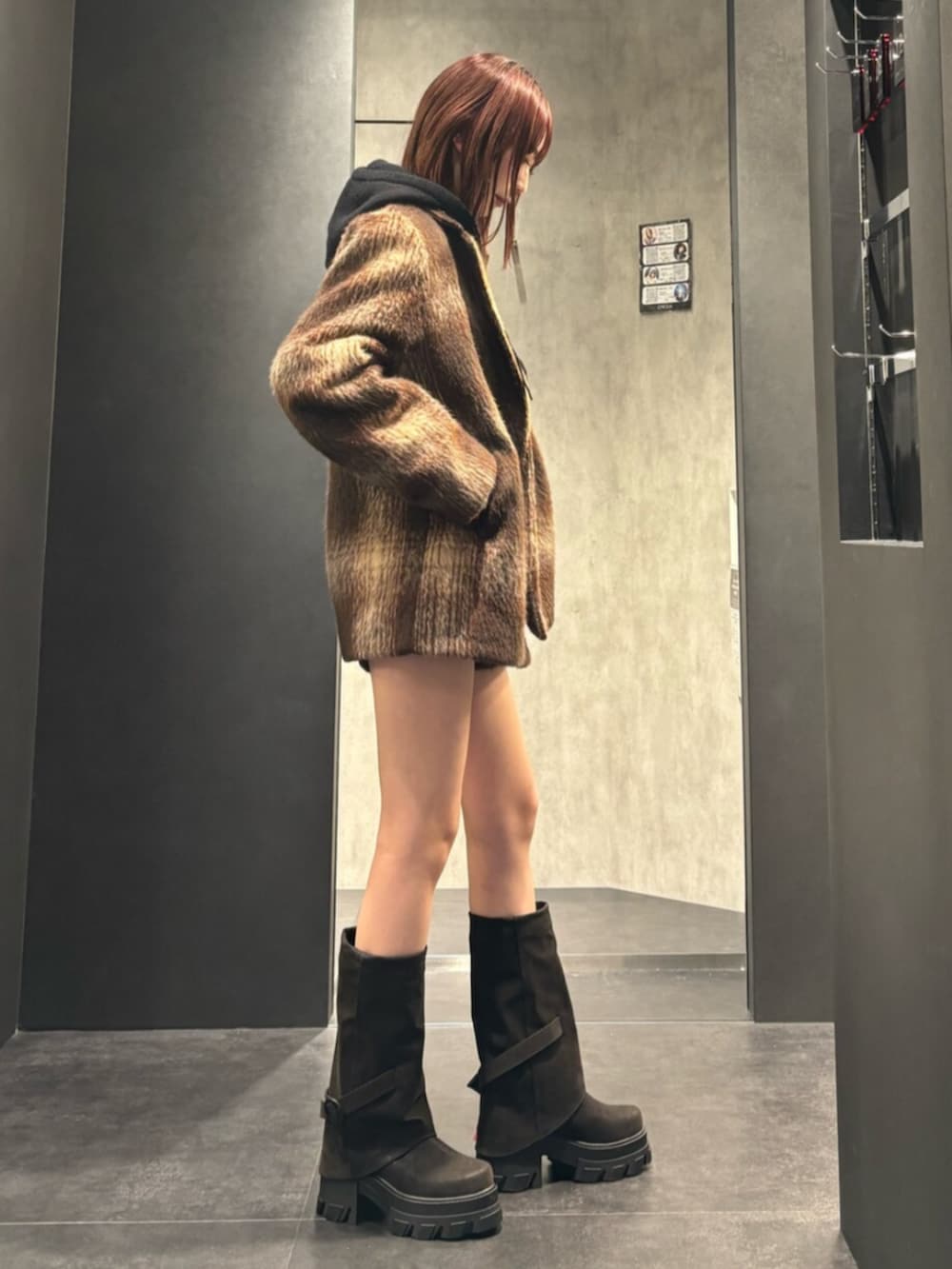 ブラック系のブーツ、ブラウン系のその他アウター、ブラック系のパーカーを着用したレディースの冬コーディネートの3枚目の写真