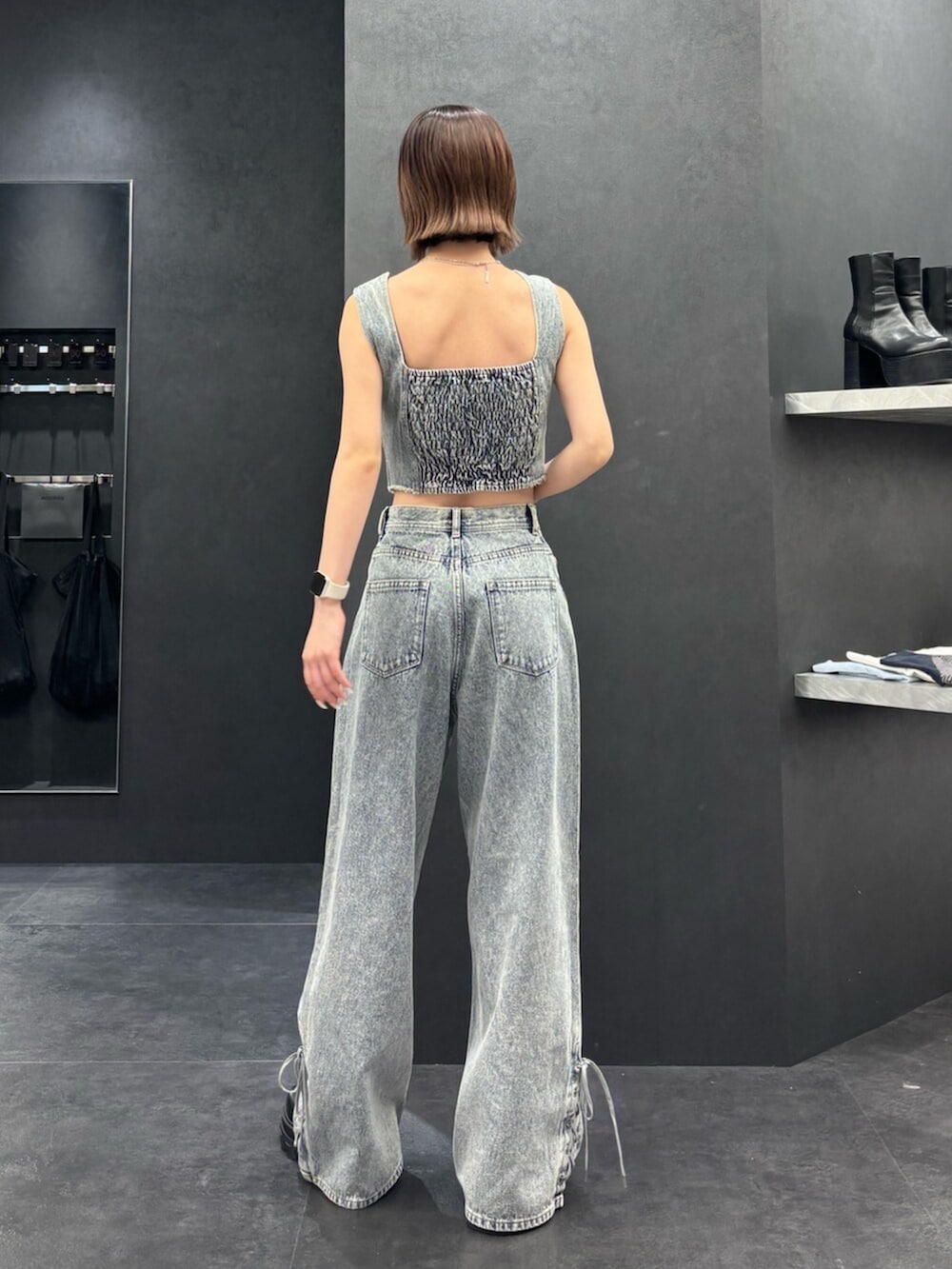 ブラック系のブーツ、ブルー系のタンクトップ、ブルー系のデニムパンツを着用したレディースの春コーディネートの3枚目の写真