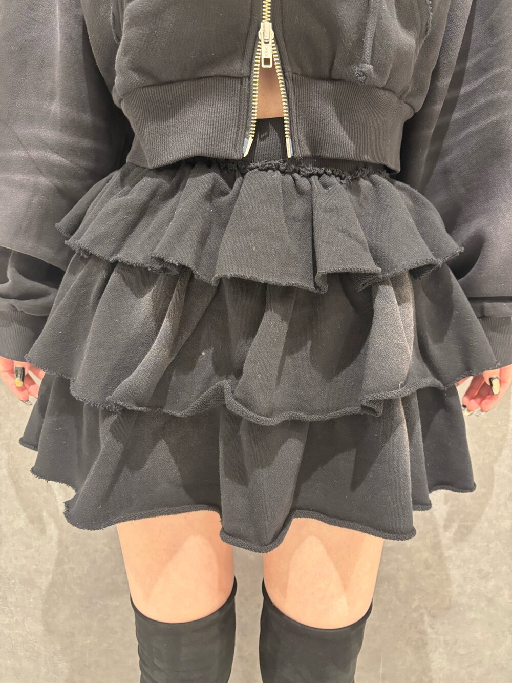 ブラック系のパーカー、ブラック系のスカート、ブラック系のブーツを着用したレディースの秋コーディネートの6枚目の写真