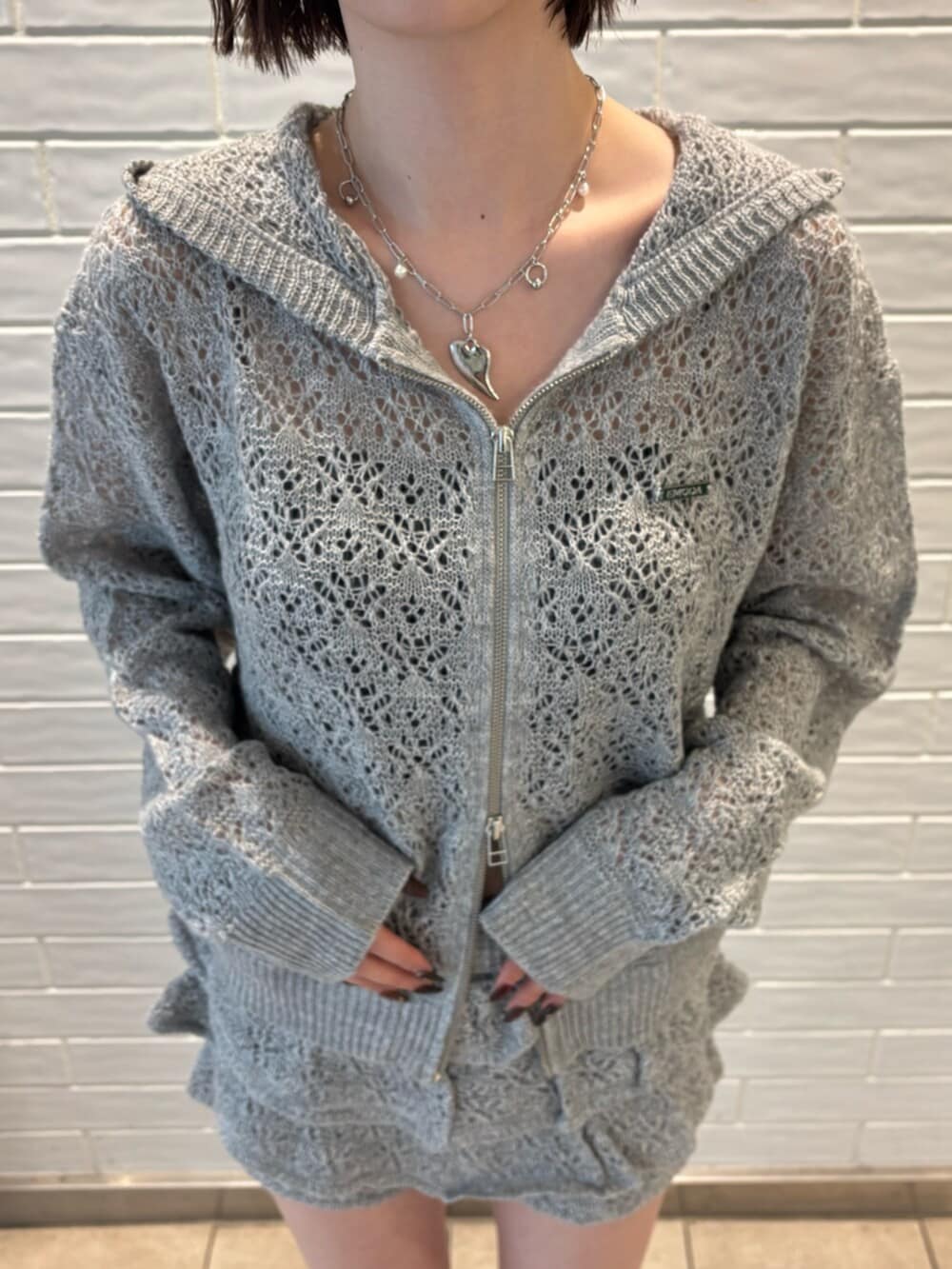 グレー系のパーカー、グレー系のスカート、ブラック系のサンダルを着用したレディースの春コーディネートの4枚目の写真