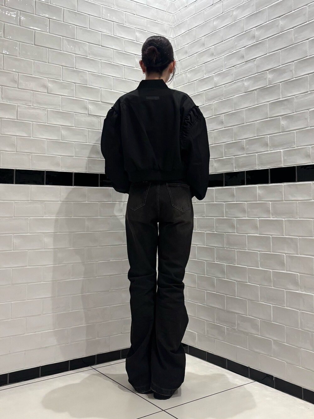 ブラック系のデニムパンツ、ブラック系のスリッポン、ブラック系のブルゾンを着用したレディースの秋コーディネートの3枚目の写真