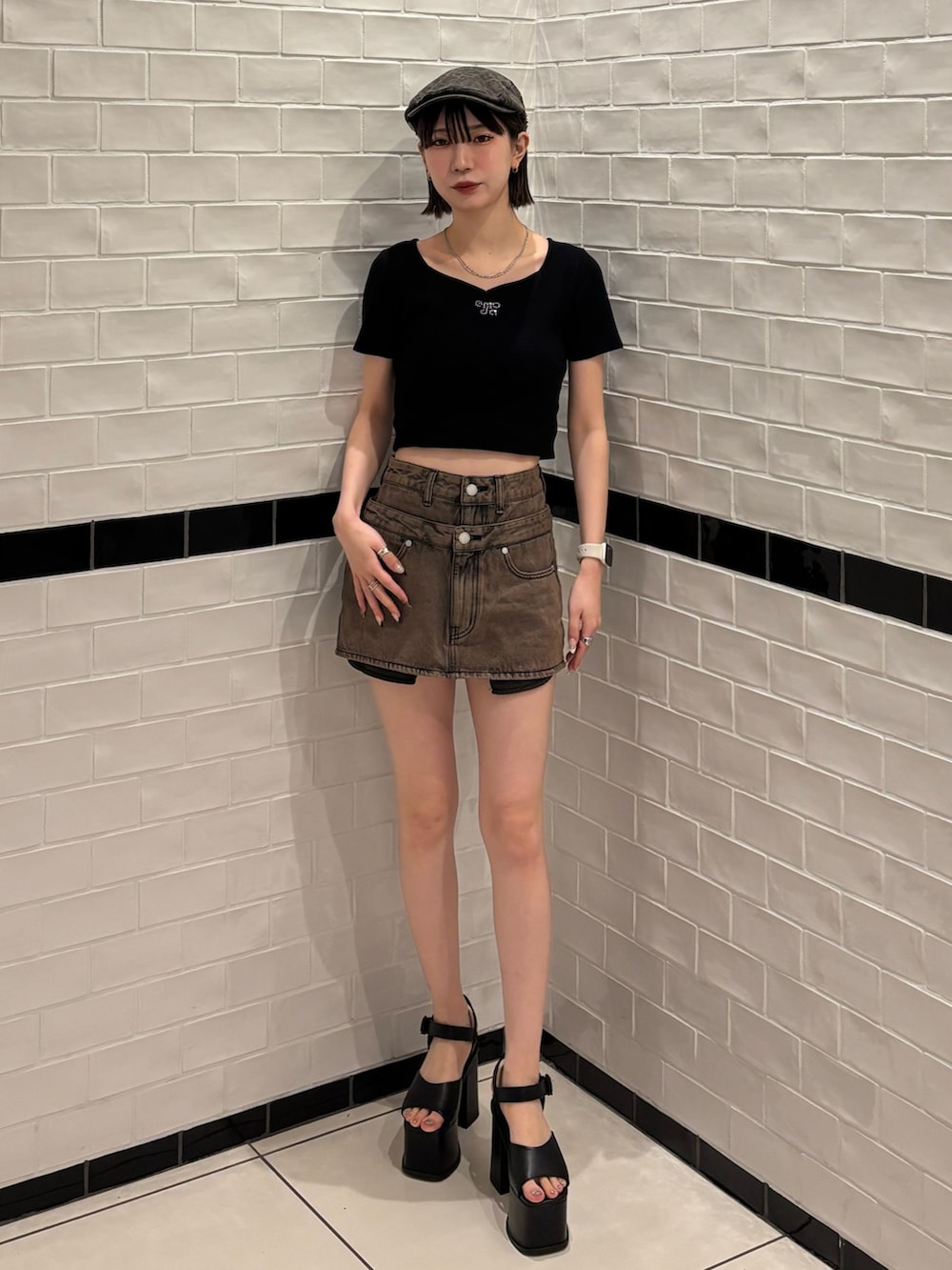 ブラック系のニット/セーター、ブラウン系のスカート、ブラック系のサンダルを着用したレディースの春コーディネートの2枚目の写真