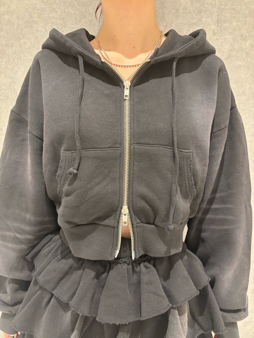 ブラック系のパーカー、ブラック系のスカート、ブラック系のブーツを着用したレディースの秋コーディネートの5枚目の写真