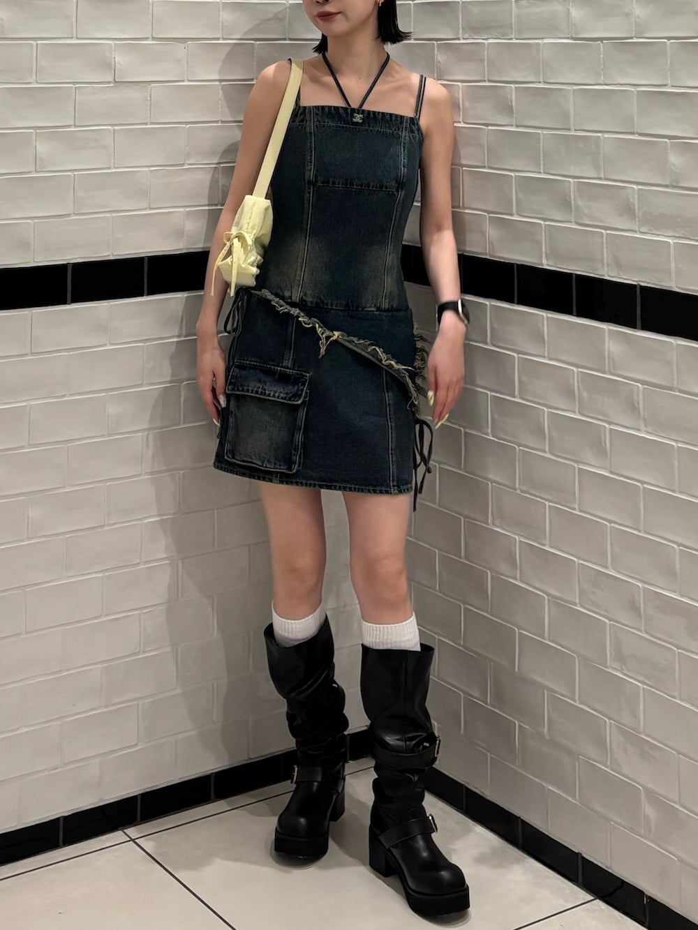 ブルー系のワンピース、ブラック系のハンドバッグ、ブラック系のブーツを着用したレディースの春コーディネートの2枚目の写真