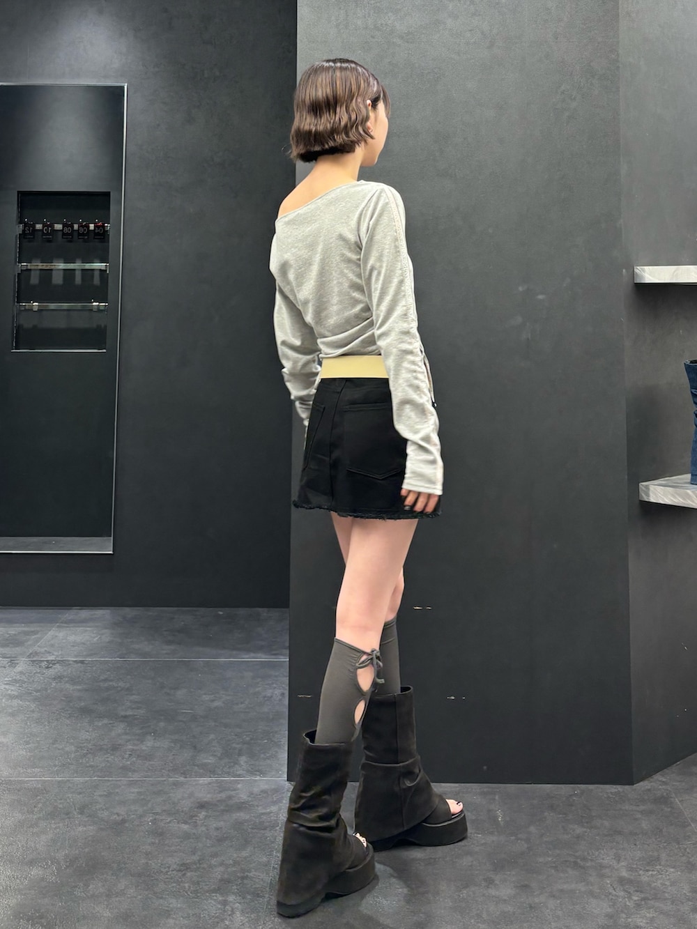 ブラック系のスカート、ブラック系のサンダル、グレー系のTシャツ/カットソーを着用したレディースの春コーディネートの2枚目の写真