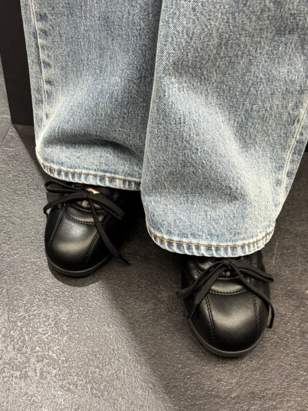 ブラック系のスニーカー、ブルー系のデニムパンツ、ブラック系のニット/セーターを着用したレディースの春コーディネートの6枚目の写真