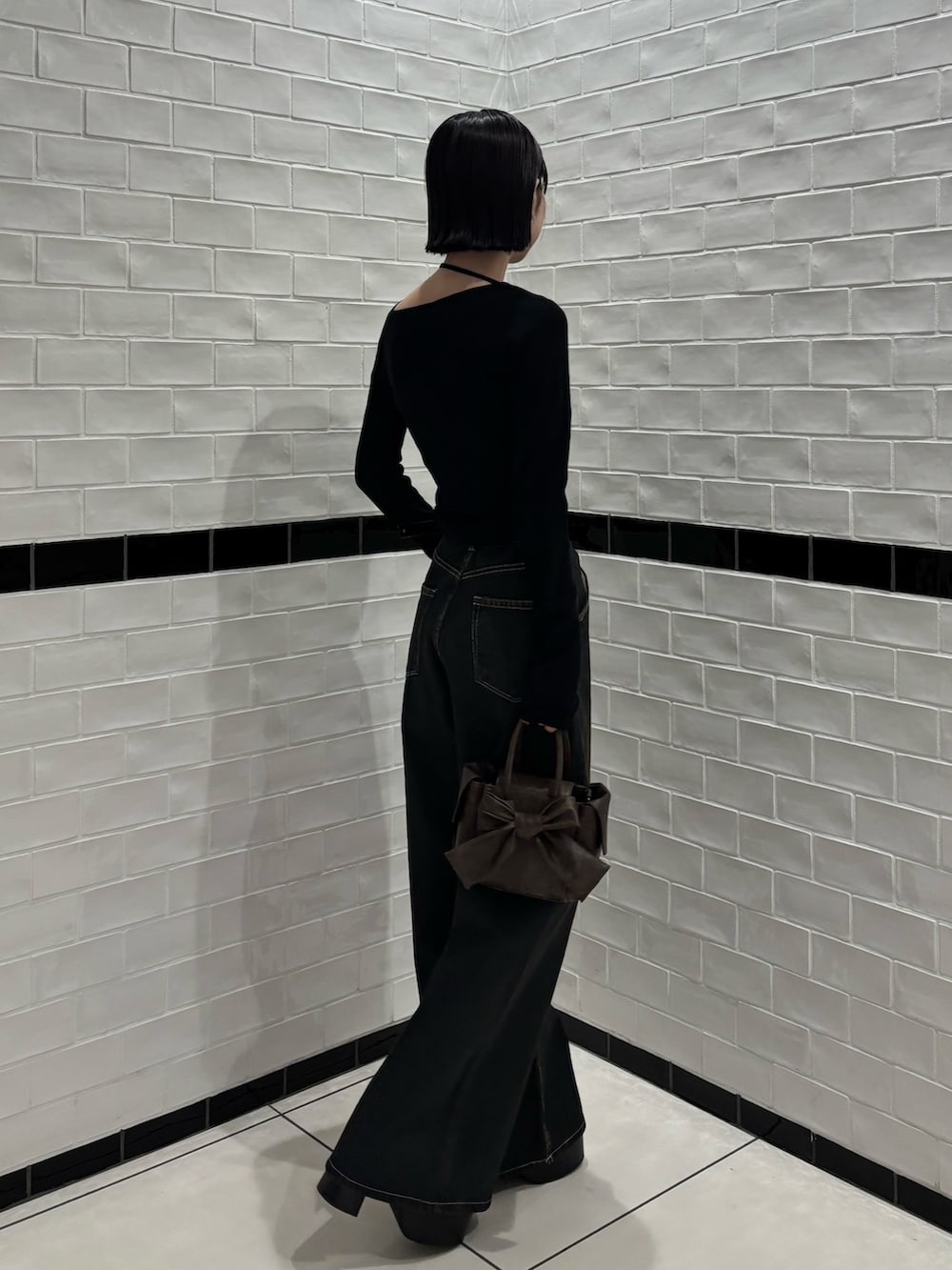 ブラック系のニット/セーター、ブルー系のデニムパンツ、ブラウン系のハンドバッグを着用したレディースの冬コーディネートの2枚目の写真