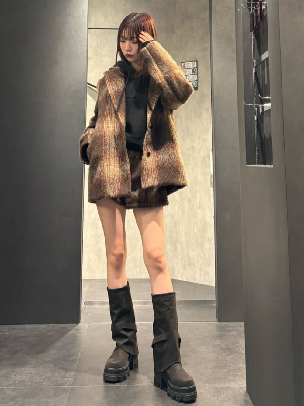 ブラック系のブーツ、ブラウン系のその他アウター、ブラック系のパーカーを着用したレディースの冬コーディネートの2枚目の写真