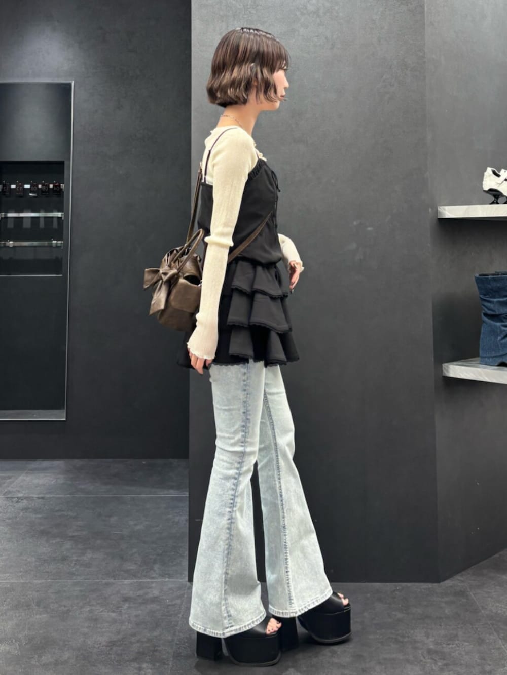 ブラウン系のハンドバッグ、ブラック系のサンダル、ブルー系のデニムパンツを着用したレディースの春コーディネートの2枚目の写真