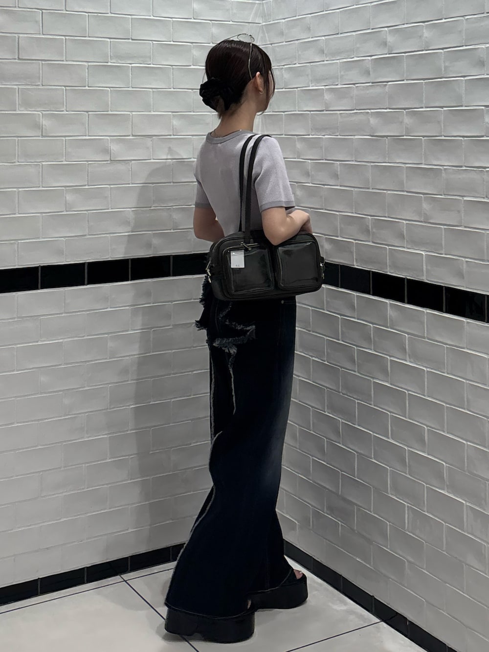 ピンク系のニット/セーター、ブルー系のデニムパンツ、ブラック系のショルダーバッグを着用したレディースの夏コーディネートの2枚目の写真