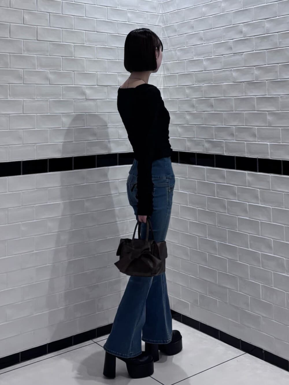 ブラック系のブーツ、ブラウン系のハンドバッグ、ブラック系のTシャツ/カットソーを着用したレディースの冬コーディネートの2枚目の写真