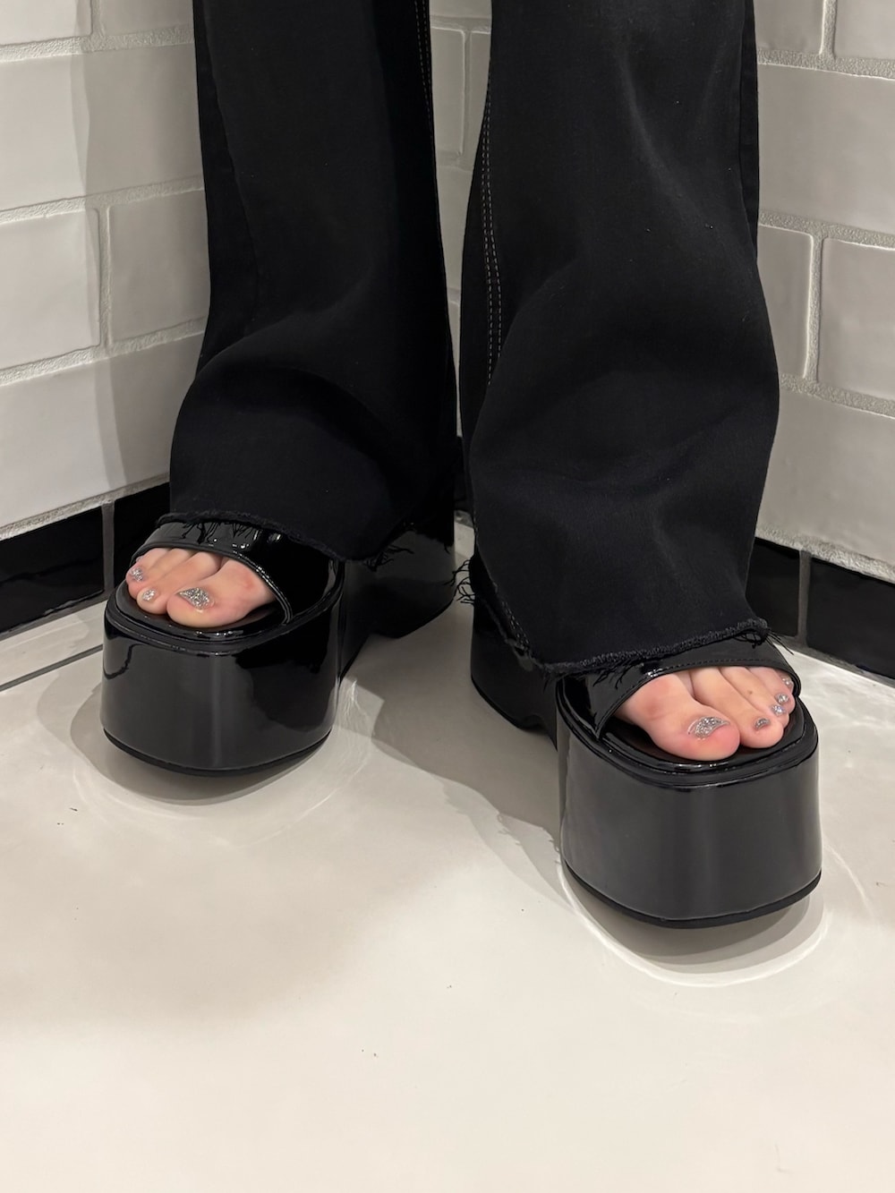 ブルー系のニット/セーター、ブラック系のデニムパンツ、ホワイト系のハンドバッグを着用したレディースの春コーディネートの6枚目の写真