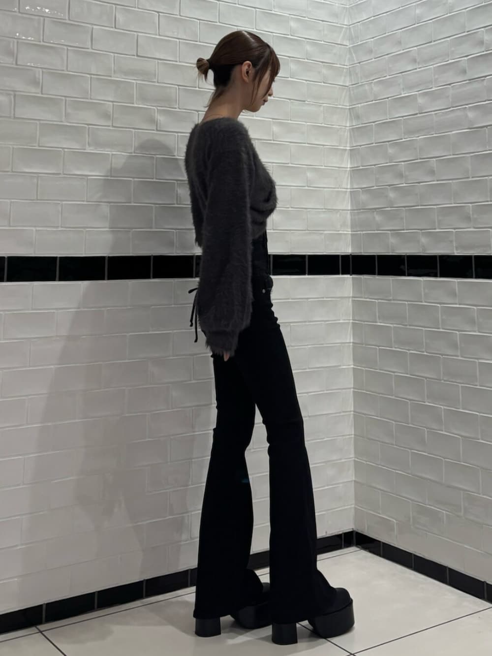 グレー系のニット/セーター、ブラック系のデニムパンツ、ブラック系のブーツを着用したレディースの秋コーディネートの2枚目の写真