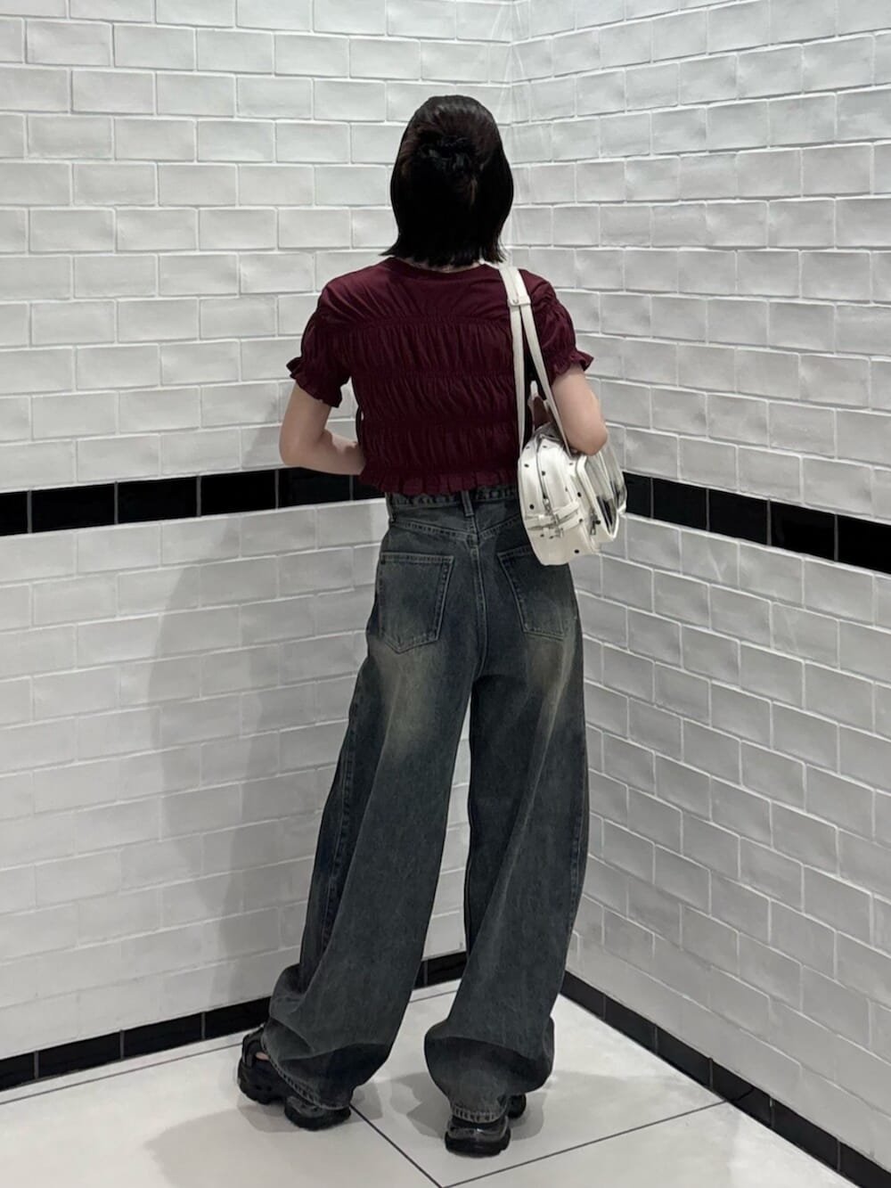 ホワイト系のショルダーバッグ、ブラック系のサンダル、ブルー系のデニムパンツを着用したレディースの夏コーディネートの3枚目の写真