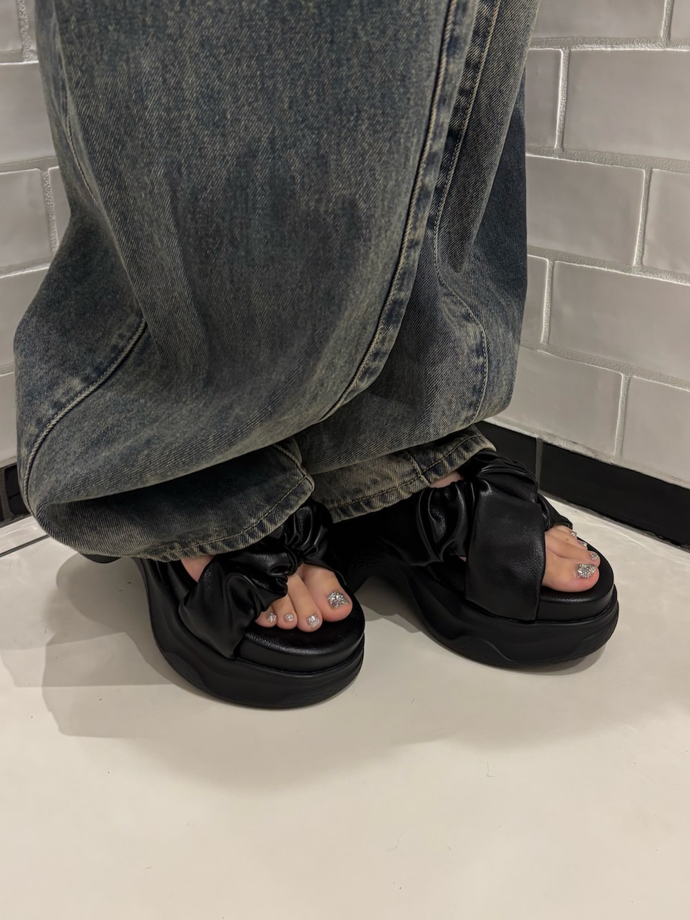 ホワイト系のタンクトップ、ブルー系のデニムパンツ、ブラック系のショルダーバッグを着用したレディースの夏コーディネートの6枚目の写真