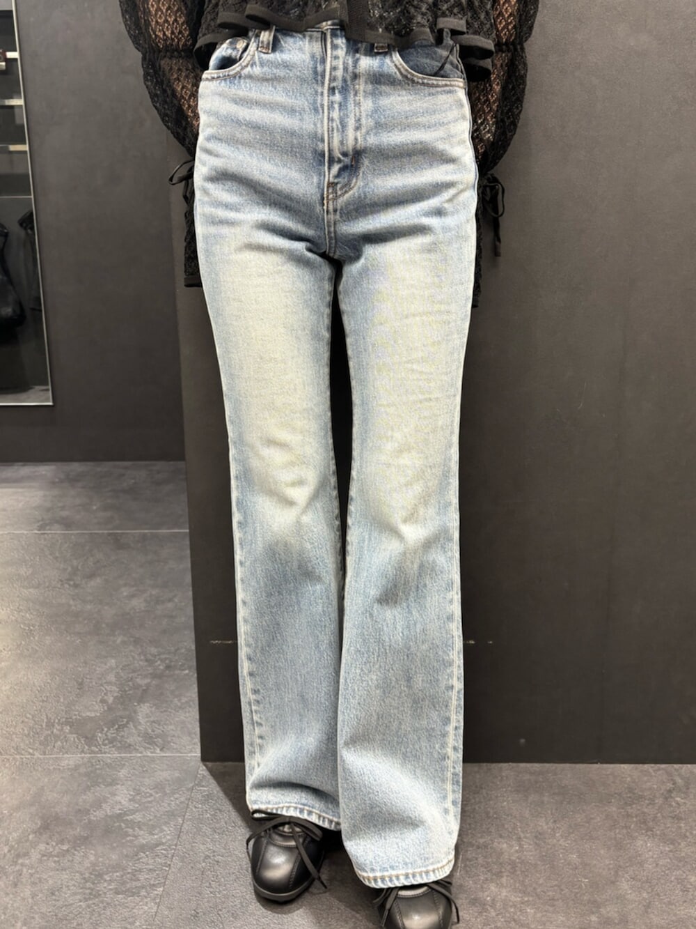 ブラック系のスニーカー、ブルー系のデニムパンツ、ベージュ系のシャツ/ブラウスを着用したレディースの春コーディネートの5枚目の写真