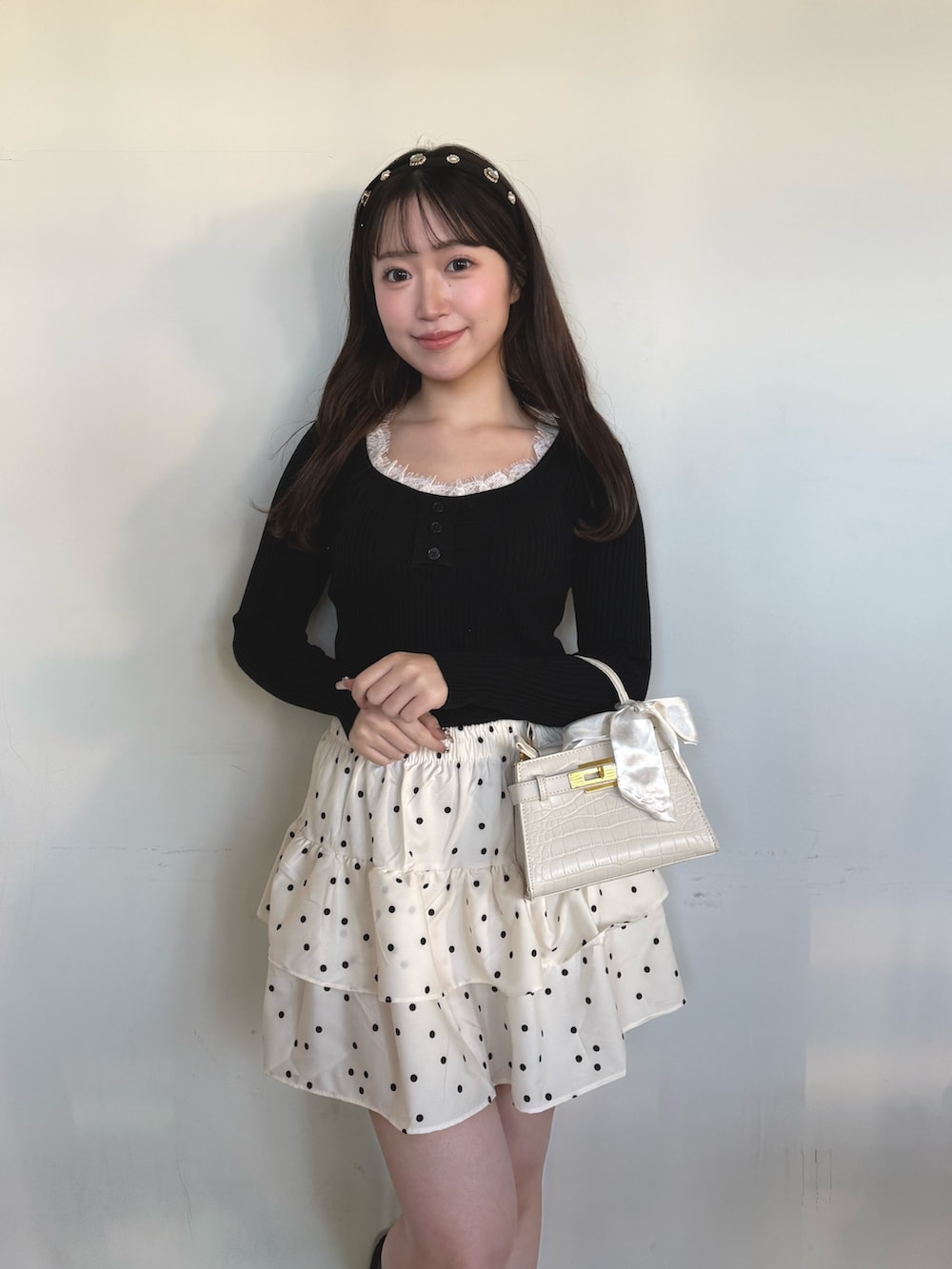 ブラック系のニット/セーター、ホワイト系のスカートを着用したレディースの冬コーディネートの2枚目の写真