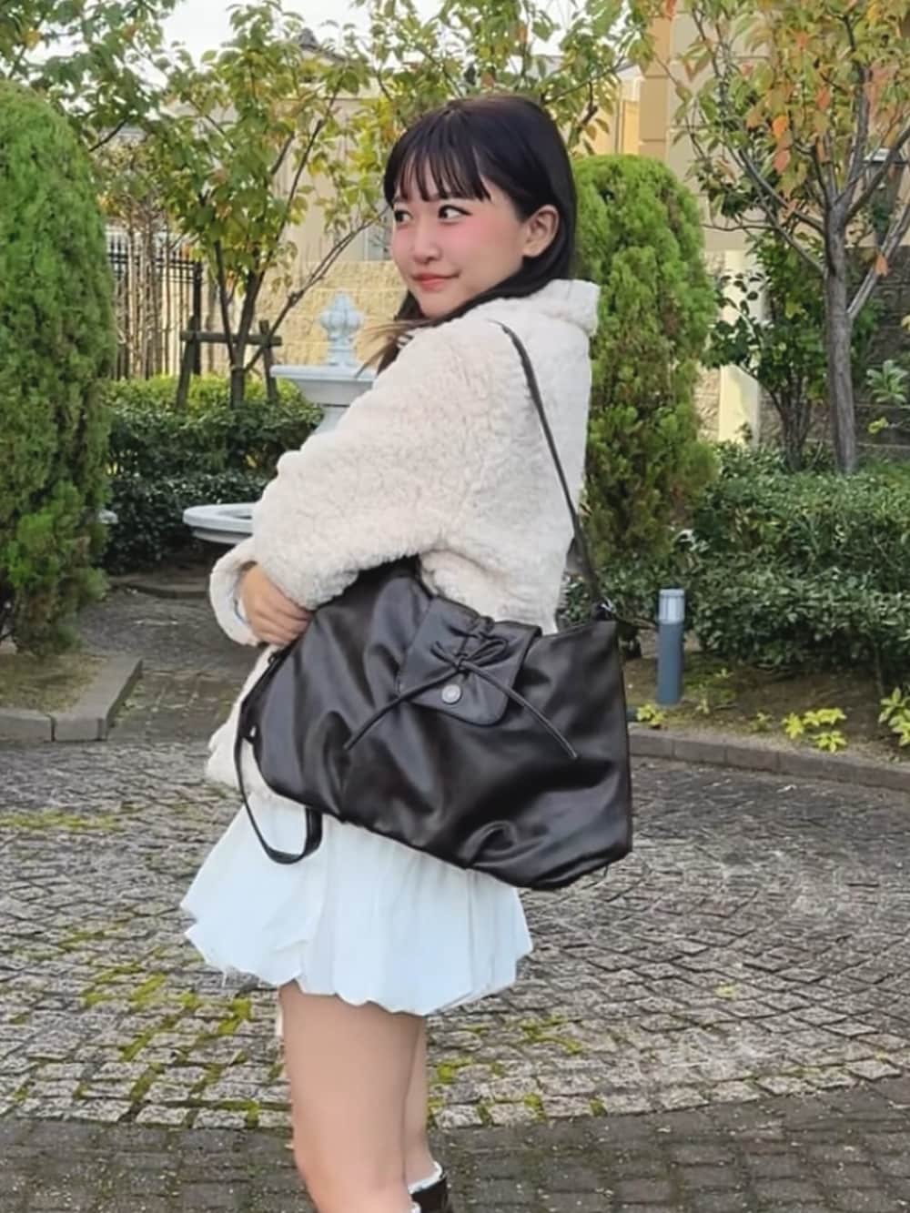 ブラウン系のショルダーバッグを着用したレディースの冬コーディネートの2枚目の写真