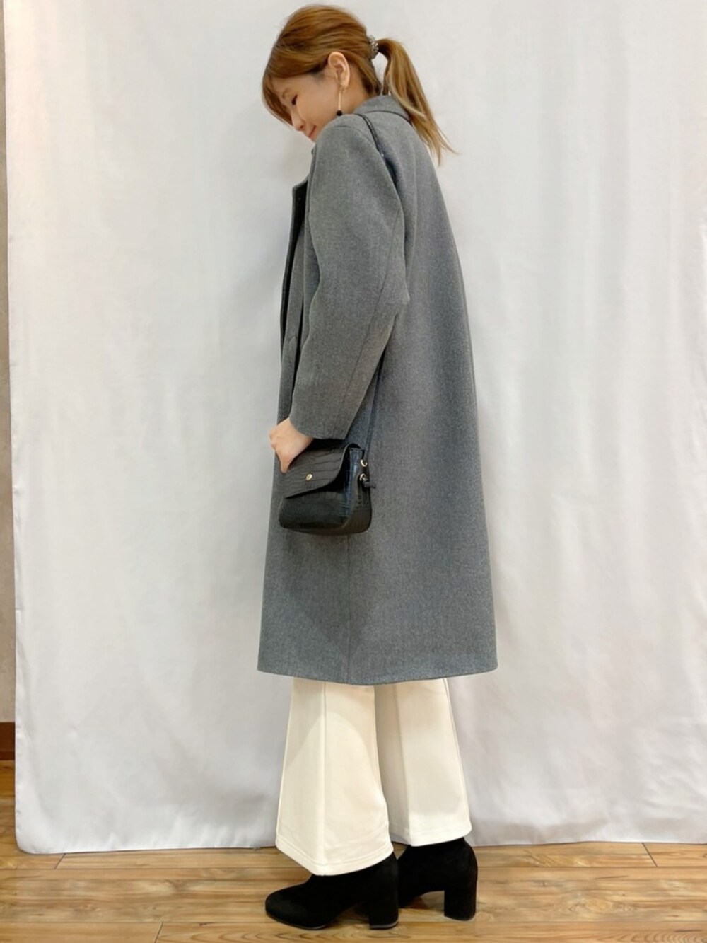 ブルー系のニット/セーター、グレー系のダウンジャケット/コート、ブラック系のショルダーバッグを着用したレディースの秋コーディネートの3枚目の写真