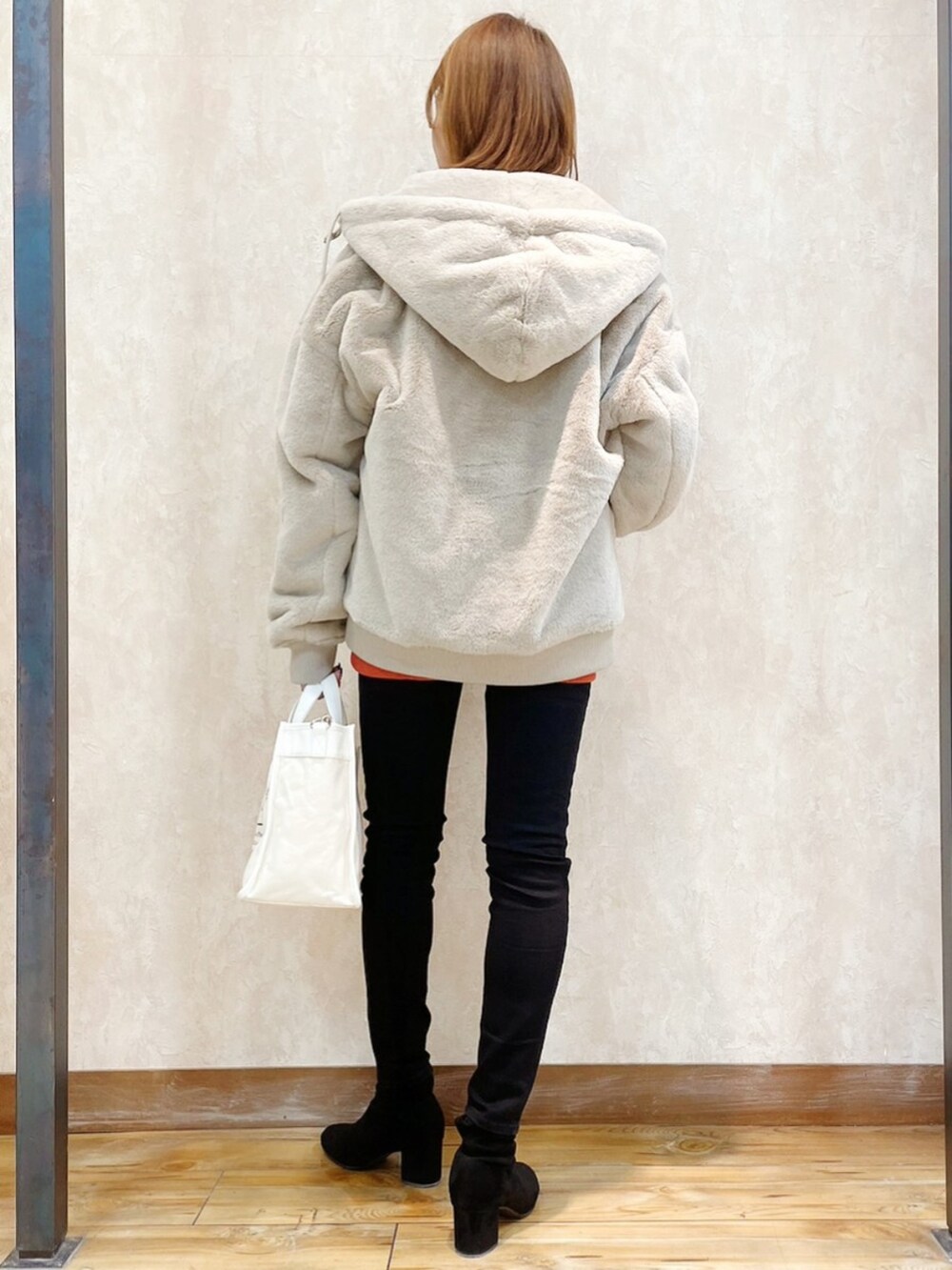 オレンジ系のスウェット、ブラック系のパンツ、ホワイト系のショルダーバッグを着用したレディースの冬コーディネートの5枚目の写真