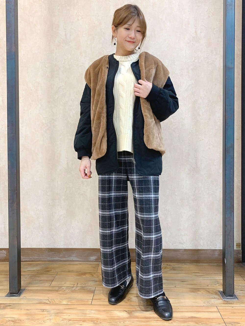 ホワイト系のニット/セーター、ブラック系のダウンジャケット/コート、グレー系のスラックスを着用したレディースの秋コーディネートの2枚目の写真