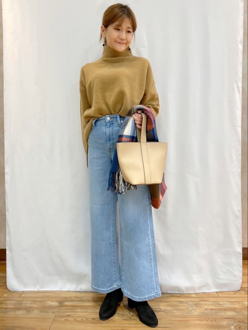 イエロー系のニット/セーター、ブルー系のデニムパンツ、その他のマフラーを着用したレディースの秋コーディネートの4枚目の写真