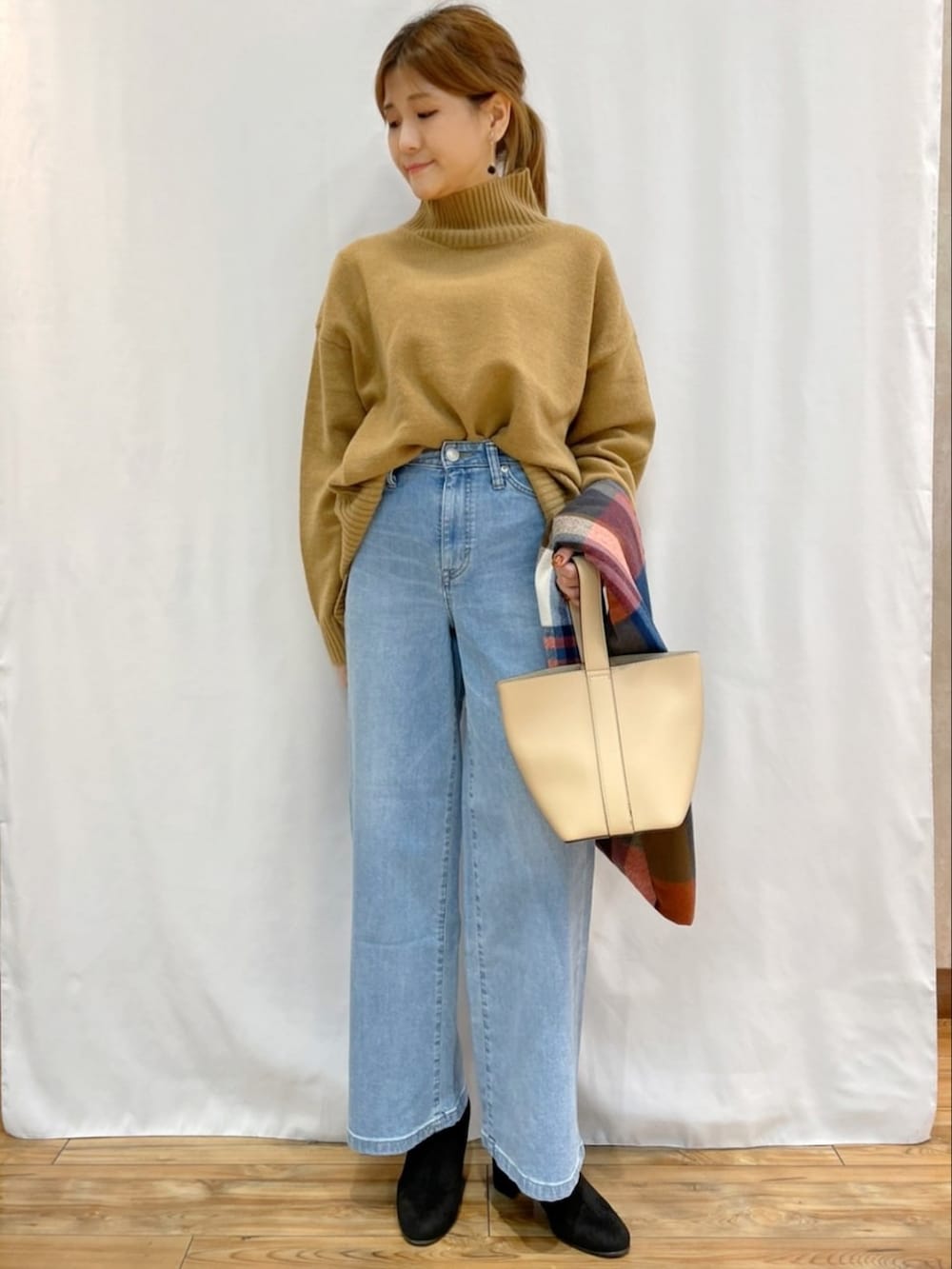 イエロー系のニット/セーター、ブルー系のデニムパンツ、その他のマフラーを着用したレディースの秋コーディネートの5枚目の写真