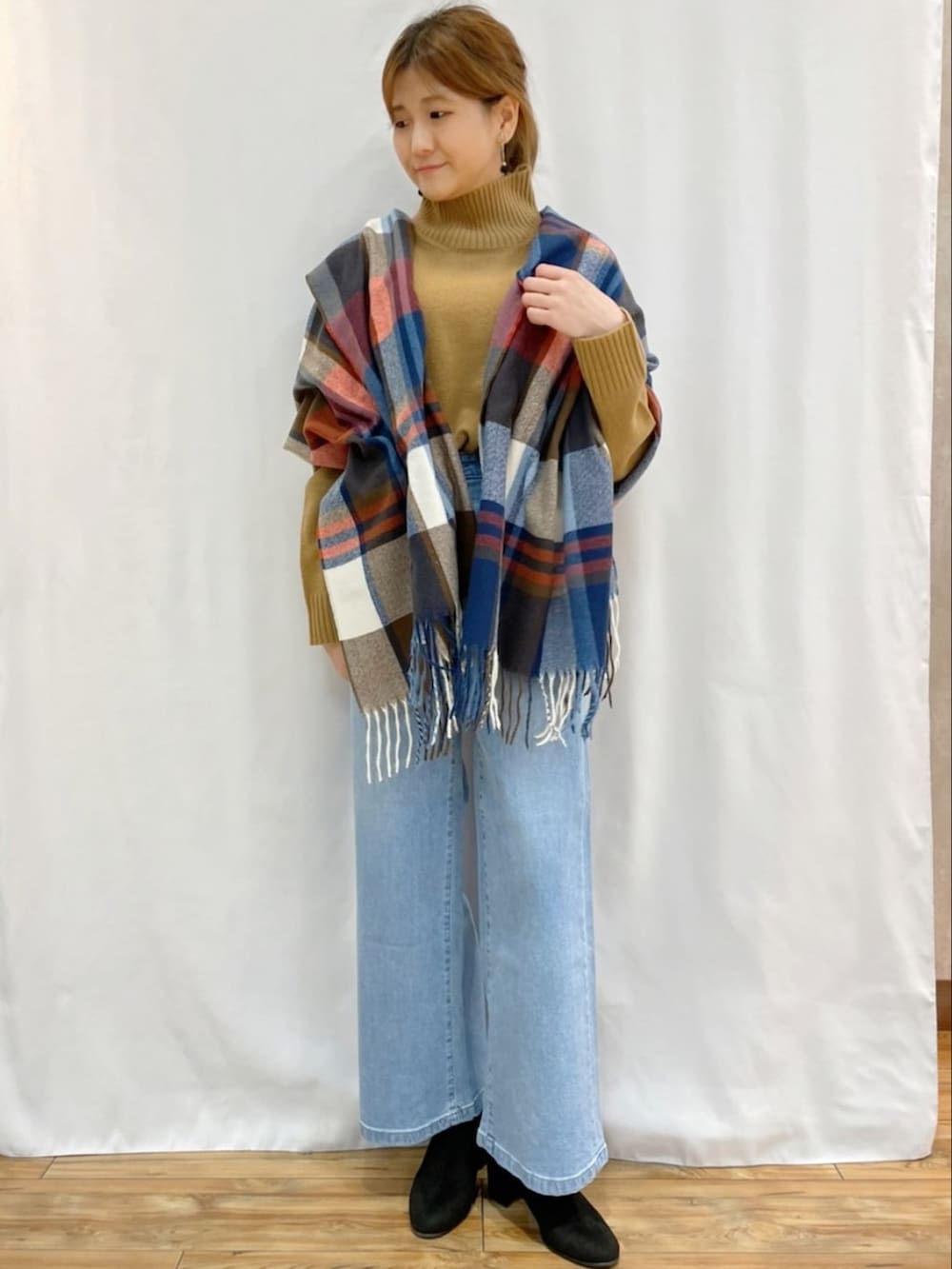 イエロー系のニット/セーター、ブルー系のデニムパンツ、その他のマフラーを着用したレディースの秋コーディネートの2枚目の写真