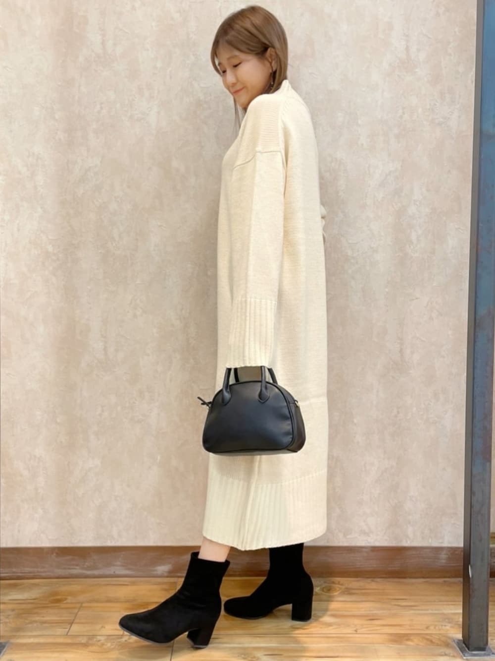 ホワイト系のワンピース、グレー系のダウンジャケット/コート、ブラック系のバッグを着用したレディースの冬コーディネートの5枚目の写真